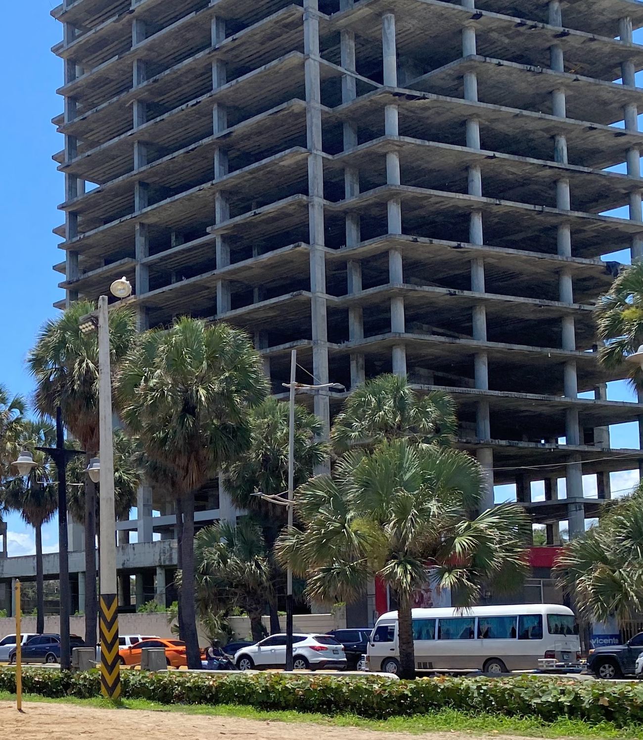 Estructura de hormigón de una torre sin terminar, entre palmeras